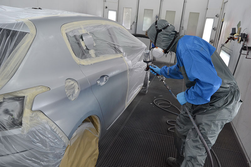 Autospuiter aan het werk in de spuitcabine